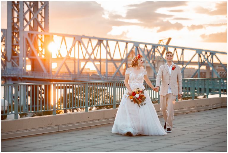Bride and groom in front of bridge during sunset