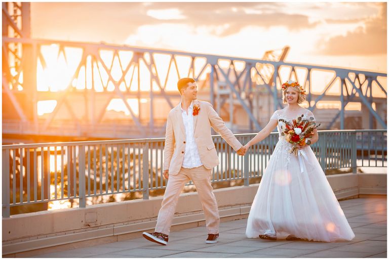 Bride and groom in front of bridge during sunset